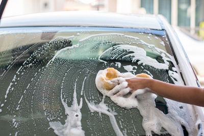 Cropped hand cleaning car windshield