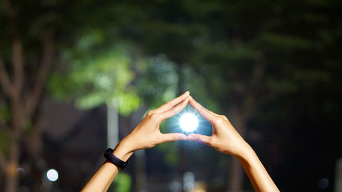 Cropped hands of woman around moon at night