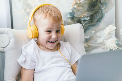 A boy in headphones looks at a laptop screen.
