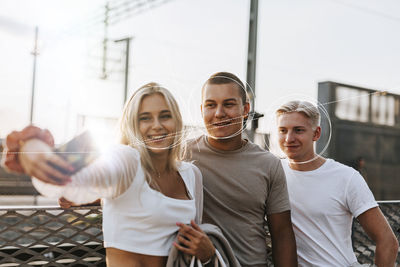 Smiling young friends taking selfie with smart phone