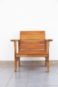 Empty wooden chair against white wall