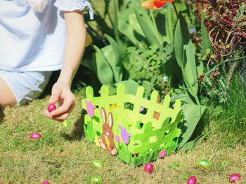 Hands caucasian teenage girl lays a chocolate easter egg in a green easter felt basket