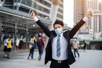 Businessman wearing mask standing against building on street