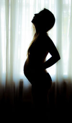 Rear view of woman standing against curtain