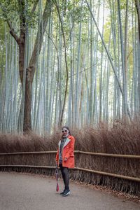 Portrait of woman standing on road in forest