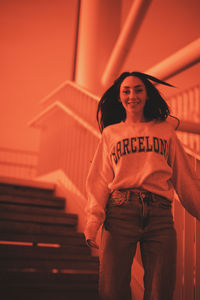 Portrait of young woman standing against wall