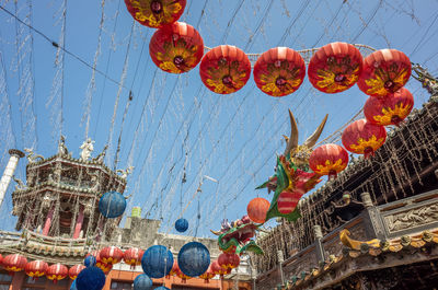 Low angle view of lanterns hanging by building against sky