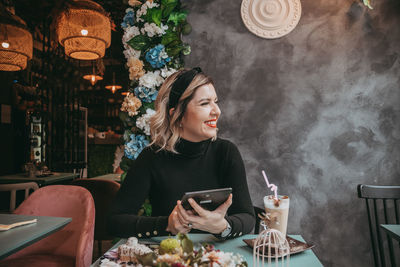 Young woman using phone while sitting on table