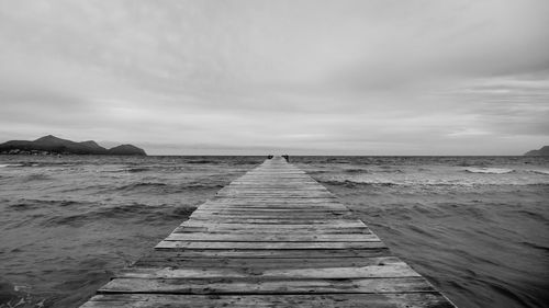 Pier over sea against cloudy sky