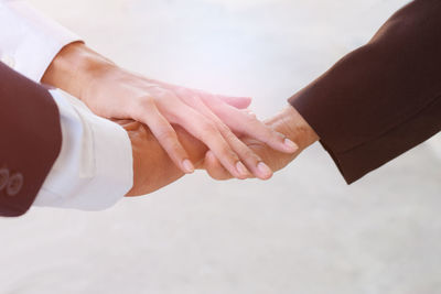 Cropped image of colleagues stacking hands against white background