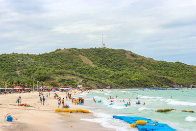 People enjoying on beach against mountain