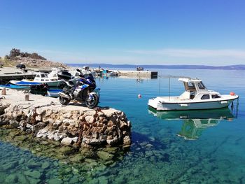 Boats moored on sea against blue sky