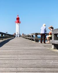 Rear view of people on pier against sky