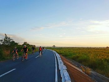 People on road amidst trees against sky