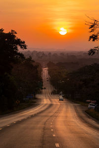 Road passing through city during sunset