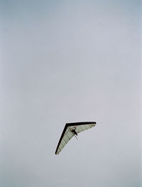 Low angle view of person hang gliding against sky