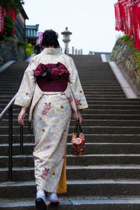 Rear view of woman in kimono walking on steps