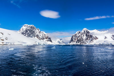 Scenic view of snowcapped mountains against blue sky