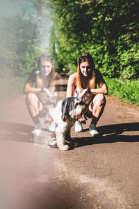 Digital composite image of woman crouching by dog on footpath reflecting in glass