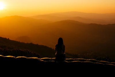 Silhouette man standing on mountain against sky during sunset