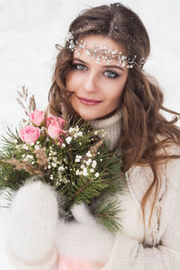 Beautiful bride in a white dress with a bouquet in a snow-covered winter forest. 