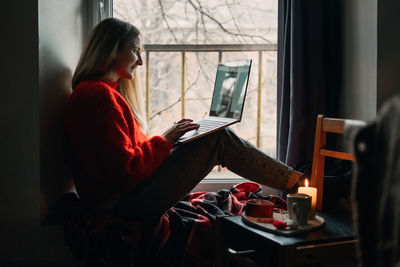 Side view of woman using laptop at home
