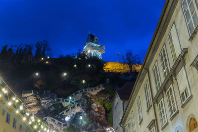 Illuminated buildings against blue sky at night