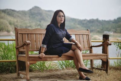 Full length of young woman sitting on bench