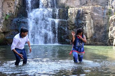 Young couple standing against waterfall in river