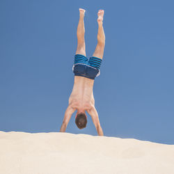 Midsection of shirtless man against blue sky