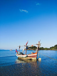 Fishing boat in sea against clear blue sky