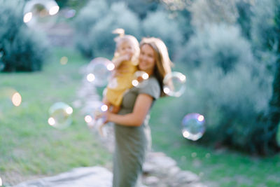 Young woman standing against blurred plants