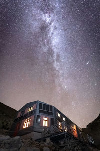 Sky full of stars with milky way above illuminated alpine hut, europe, slovakia