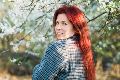 Portrait of young woman standing against trees