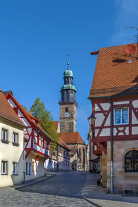 Street amidst buildings against clear blue sky