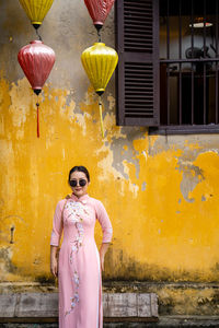 Portrait of woman standing by house