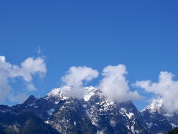 Low angle view of snowcapped mountains against blue sky