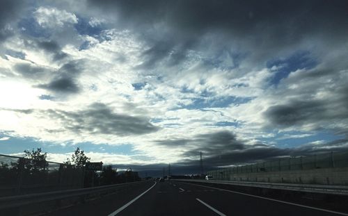 Empty road against cloudy sky