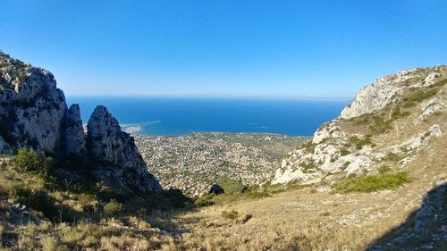 Scenic view of sea and mountains against clear blue sky