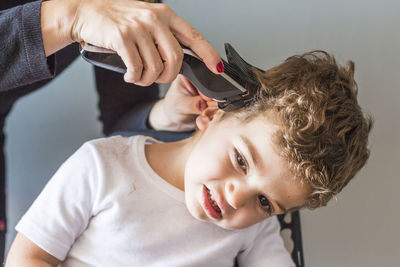 Cropped hands of hairdresser cutting boy hair