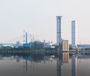 Cranes in city against clear sky