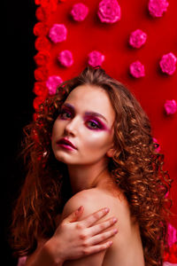 Portrait of shirtless woman in front of rose decoration against black background