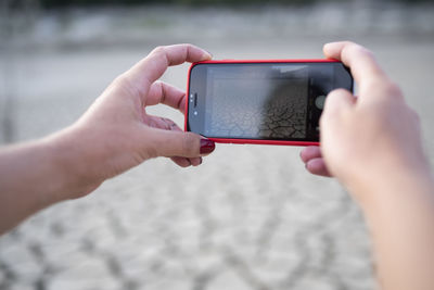 Close up of hands taking a photo with cellphone of landscape.