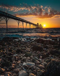 Suspension bridge over sea during sunset