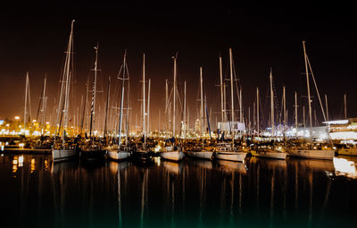 Boats moored at harbor against sky at night