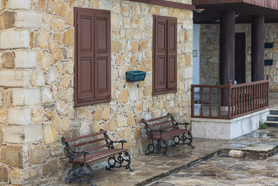 Rear view of woman sitting on bench outside house