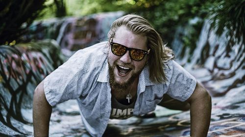 Portrait of young man wearing sunglasses doing push-ups on painted floor