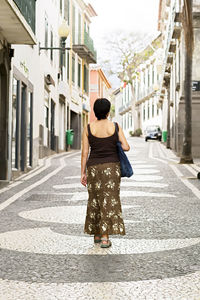 Rear view of woman walking on street amidst buildings