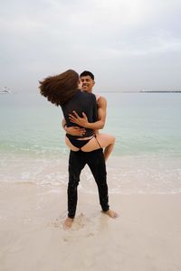 Full length of young couple having fun at the beach