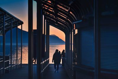 Rear view of silhouette people standing at sea against sky